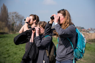 Three young people with binoculars