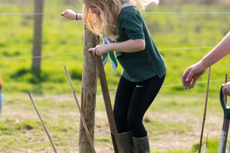 Child with blond hair on a spade planting a tree
