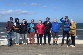 People on a seafront with visual impairment canes