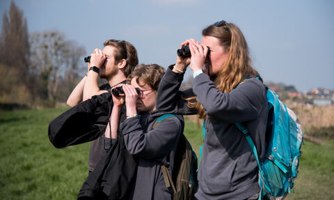 Three young people with binoculars