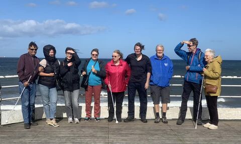 People on a seafront with visual impairment canes