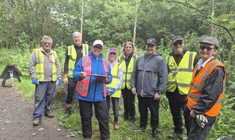 A group of smiling volunteers wearing high vis tops and gardening clothing