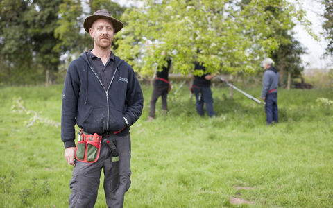 Laurence standing in an orchard