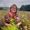 Sue Antrobus sitting in a field of wildflowers smiling