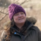 Kirsten Luckins, Tees Valley Wildlife Trust's artist in residence, smiles whilst outside in cold weather, she is wearing a purple wooly hat and dark green coat