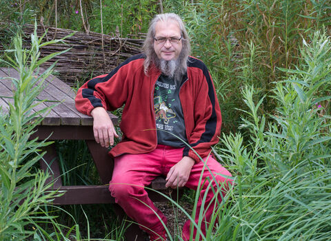 Mark sat on a bench surrounded by trees 
