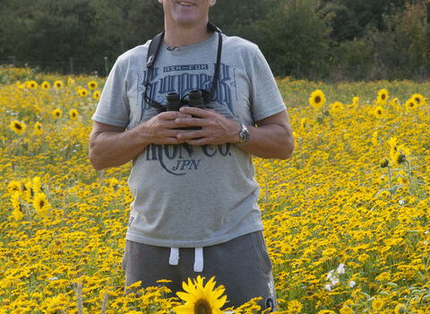 Iolo stands in a field of sunflowers